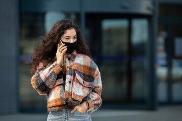 Portrait of young woman wearing safety mask. Beautiful girl with face mask using mobile phone.