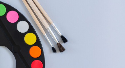 Art artist palette with paint and brushes top view on gray background