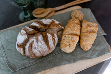 Fresh bread on the table Food for breakfast Lush from the brown oven on the background Stylish kitchen interior Wooden tray
