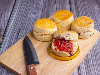 Scones traditional English delicious freshly baked homemade with strawberry jam placed on a wooden...