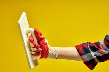 Female hand with a spatula, used for applying a layer of putty