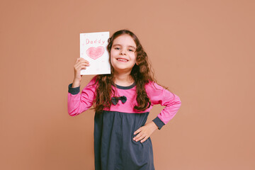 Happy family daughter girl kid giving a greeting card on holiday isolated on a beige background. Father's day. Mother's Day. Valentine's Day.