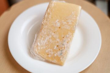 Moldy cheese wrapped in cling film. Incorrect storage, spoiled product, expired concept.