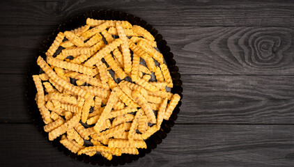 Frozen fries with spices on a black background. Preparation for cooking.