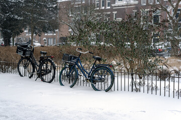 Fototapeta na wymiar Bicycles parked by a fence on a snowy street. Amsterdam, Netherlands.