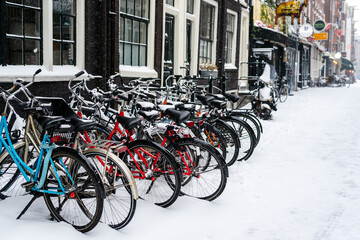 Bicycles parked at the house on a snowy street. Amsterdam, Netherlands.