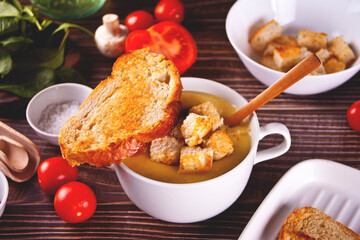 Cheese or onion cream soup with toasts bread in a white bowl