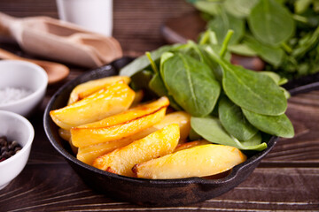 Fried potato with herbs and spices on the wooden table