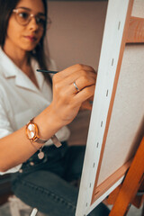 Beautiful talented female artist painting at her home.