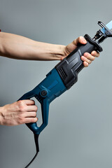 Reciprocating saw used in construction and demolition work, in male hands