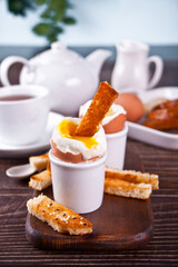 boiled egg in eggcup on wooden board with crispy toast.