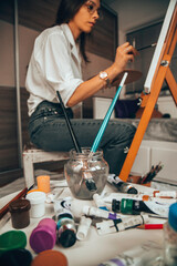 Beautiful talented female artist painting at her home.