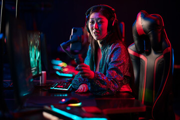 Obraz na płótnie Canvas A young beautiful asian girl is broadcasting online on a smartphone with the help of a three-axis stabilizer. Female gamer at the esports tournament.
