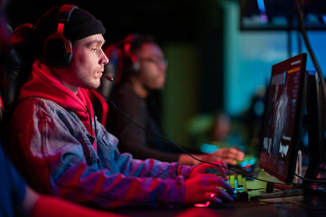International gaming event. Arena for conducting esports competitions. Young players with headphones are playing a popular online game.
