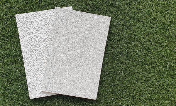 exterior grungy wall ,by textured spray paint for rough surface, samples placed on artificial grass with space for text. textured concrete plaster with spraying in the form of drops samples. 