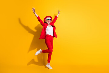 Full length body size photo of elder woman wearing stylish red suit sunglass smiling isolated on vibrant yellow color background