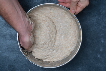 Male baker stretches out yeast-free dough for baking bread with his hands