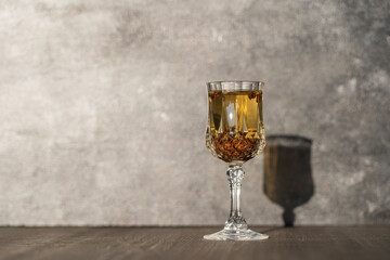 Homemade birch buds tincture in a wine crystal glass on a wooden table background