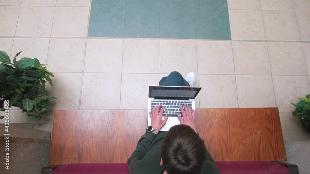 Poster using a laptop in hands while sitting on a bench. type with your hands on the keyboard. use the inte