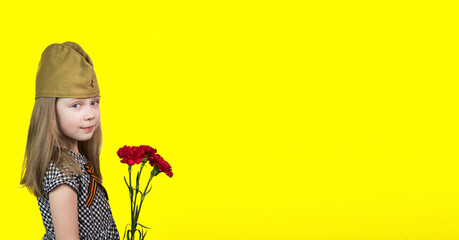 9th May. A little girl in a garrison cap with a St.George ribbon with red carnations stands on a...