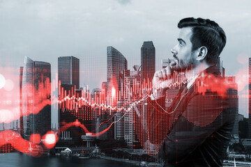 Fototapeta premium A young Caucasian handsome trader and stock market analyst in suit dreaming about market behavior and forecast in crisis. Trading at corporate finance fund. Forex chart. Singapore. Double exposure