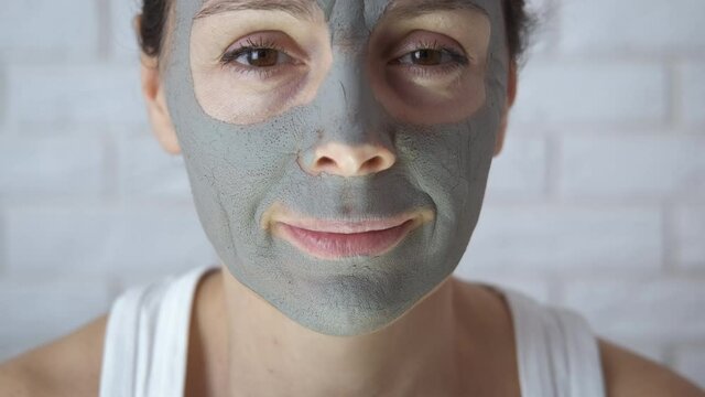 Aged woman with a clay mask on her face. A woman in her forties with cosmitic clay on her face is angry.