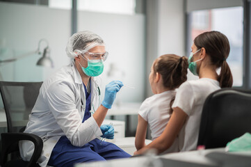 A young doctor conducts an analysis for coronavirus in the laboratory of a girl, takes a smear from the nasopharynx