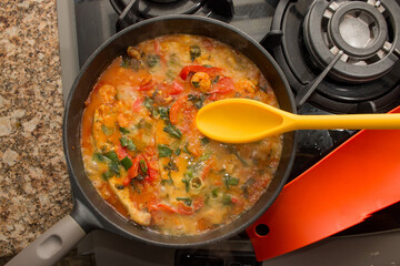 Brazilian seafood fish stew ( moqueca) cooking on the stove in an iron skillet