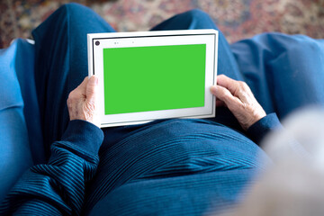 Hands of old person, senior hold tablet device with green screen. Elderly woman talking online with her family and grandchild. Study new technology for person
