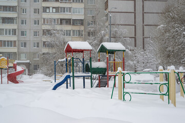 childrens play complex and bench in snow around the building