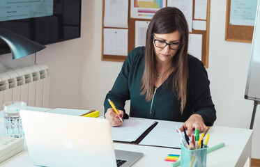 Female professor holding online class for e-learning students and writing down notes.
Teacher...