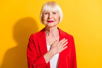 Photo of aged woman happy smile hand on heart appreciate trust promise isolated over yellow color...