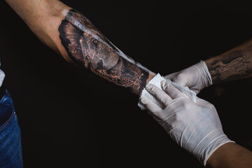 The tattoo artist finishes his work and rubs the oil on the skin