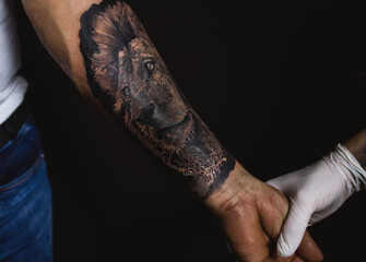 The tatoo artist checking the drawing on the hand after the job is done