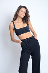 Naklejka premium Young Polish woman in studio. Slim woman with dark hairs wearing black top and black trousers.
