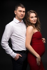 Elegant loving couple expecting baby looking at camera
