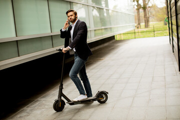 Young businessman using mobile phone  on electric scooter
