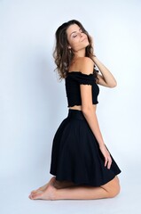 Fototapeta premium Young Polish woman in studio. Slim woman with dark hairs wearing black top and black skirt.
