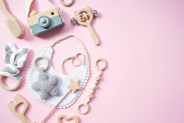 Bib and wooden toys. Set of baby stuff and accessories for girl on pastel pink background. Fashion...