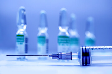Syringe and ampoules with virus vaccine close-up