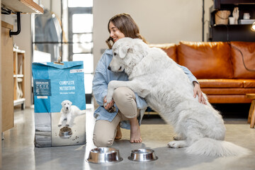 Woman feeding dog with a dry food at home