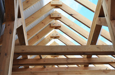 Wooden roof framing with a close-up of rafters, roof beams and purlins framing during roofing construction.