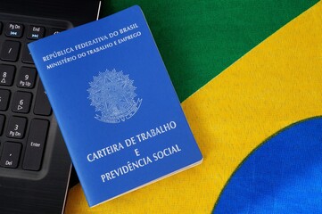 Brazilian work card (carteira de trabalho) and laptop computer on top of Brazilian flag. Formal job in Brazil.