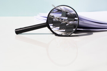 Scanning business documents. Magnifying glass on the stack of documents.