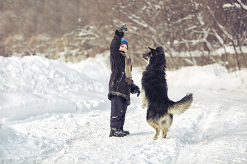 Boy playing with a dog in winter on the street