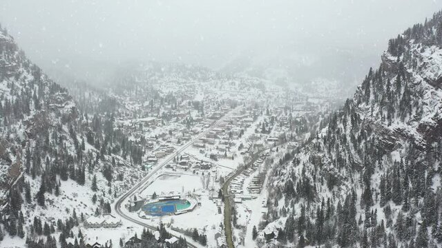 Aerial view of Ouray, Colorado USA, valley town and hot geothermal spring water pools in white foggy snowy winter landscape, drone shot