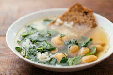 Healthy soup with Swiss chard, mint, oregano, parsley and large white beans with toasted wholegrain bread and garnished with grated vegan cheese.