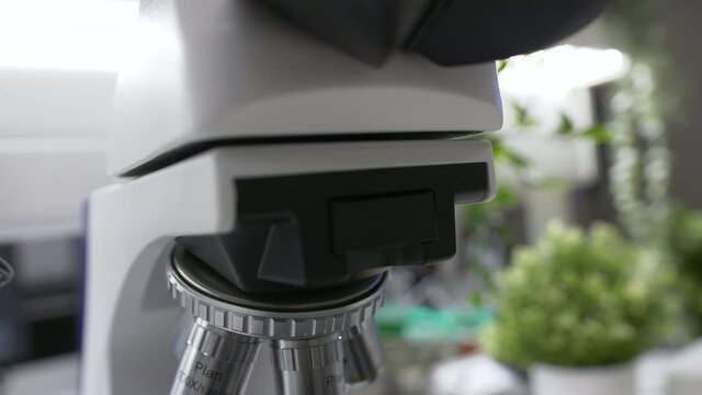 Close up of a microscope in a laboratory. White lighting in a dark lab room in slow motion in 4K. Biochemistry, pharmaceutical medicine and science.