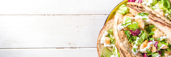 Mediterranean food. Doner Kebap, Taco, Shawarma, greek wrapped gyros sandwich, tortilla pita bread stuffed grilled chicken meat, fresh vegetables, tsatziki sauce. Sunny white wooden table copy space