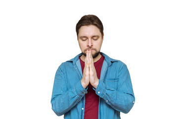 a young Caucasian man with his eyes closed joined his two palms in front of him in a namaste sign...